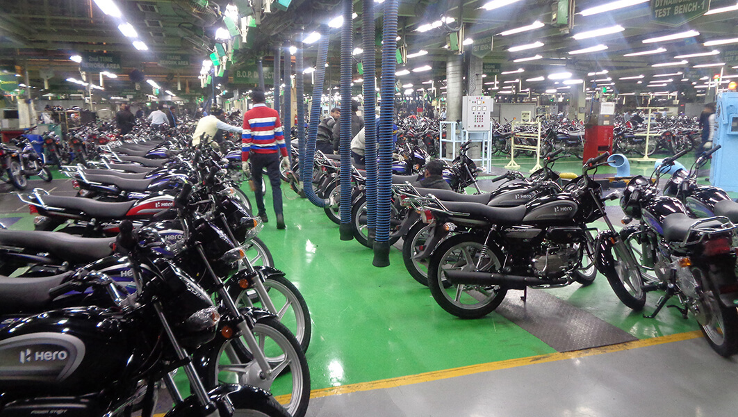 A worker walks among rows of motorcycles inside of a manufacturing facility