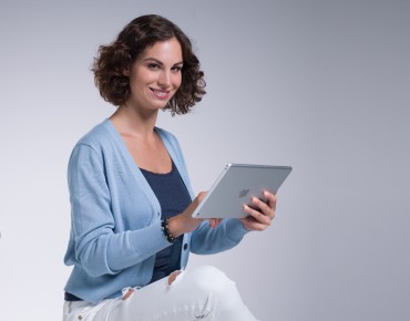 Eine Frau sitztend mit einem Tablet in der Hand