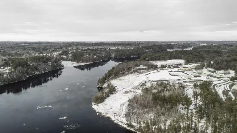 A river flows through a flat forested landscape covered in snow