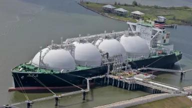 An aerial view of a large liquefied natural gas (LNG) tanker ship docked near homes