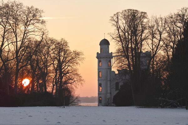 Blick auf das Schloss auf der Pfaueninsel im Winter mit Sonnenuntergang