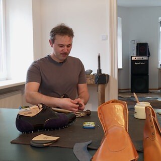 Junger Mann in Atelier fertig Maßschuhe.