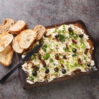 Butter Board mit Oliven, Frühlingszwiebeln und getrockneten Tomaten