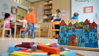 Spielzeug liegt in einer Kindertagesstätte auf dem Boden; im Hintergrund spielende Kinder: Knapp ein Prozent aller Kinder und Jugendlichen in Deutschland leben mit verschiedenen Ausprägungen von Autismus. Das fordert viele Kindergärten und Schulen besonders heraus.