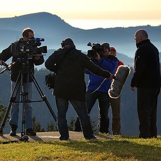 Ein SWR Team beim Dreh. Im Hintergrund ist ein in Nebel gehülltes Bergpanorama zu sehen.