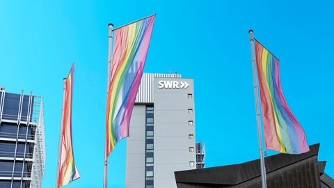 Das Bild zeigt Regenbogen-Flaggen vor dem SWR Funkhaus