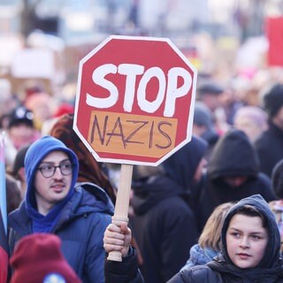 Teilnehmer der Demonstration halten ein Plakat mit der Aufschrift "Stop Nazis".