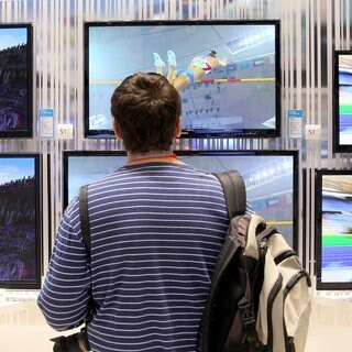 Ein Journalist betrachtet auf der IFA in Berlin in den Messehallen unter dem Funkturm Fernsehgeräte. Die Änderungen 2024 beim Kabelfernsehen in Deutschland sind vor allem für Mieter interessant.