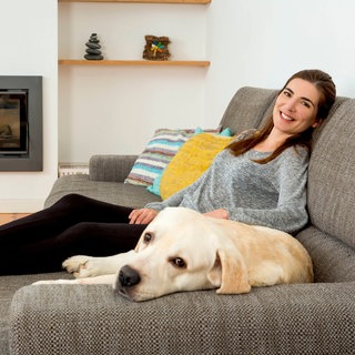 Eine Frau liegt mit ihrem Hund auf dem Sofa