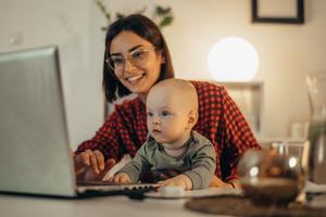 Young woman with a baby looking at a laptop