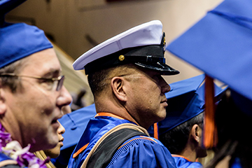 Veteran sitting at graduation surrounded by students