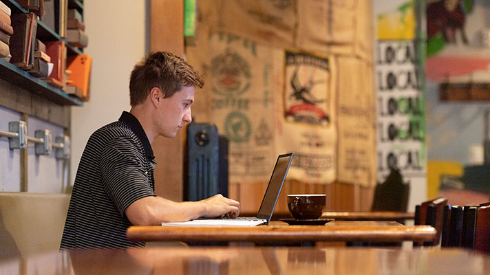 Purdue University student at table with laptop.