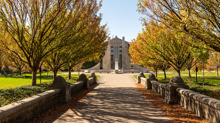 Fall trees line a walkway in the Purdue Mall leading to the Class of 1939 Water Sculpture.