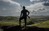 A bushmeat hunter stands on a hill looking out over the forests of southern Guinea