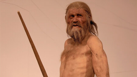 A naked old man holds a spear in his hand.