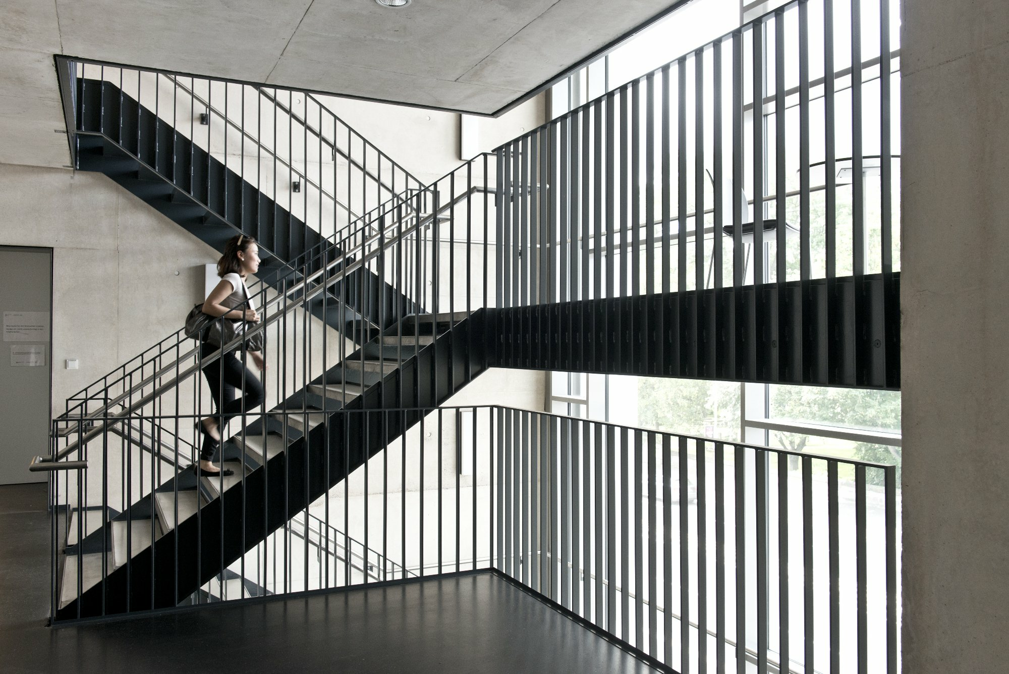 Eine Studierende geht eine Treppe im Treppenhaus des Lern- und Studiengebäudes hinauf.