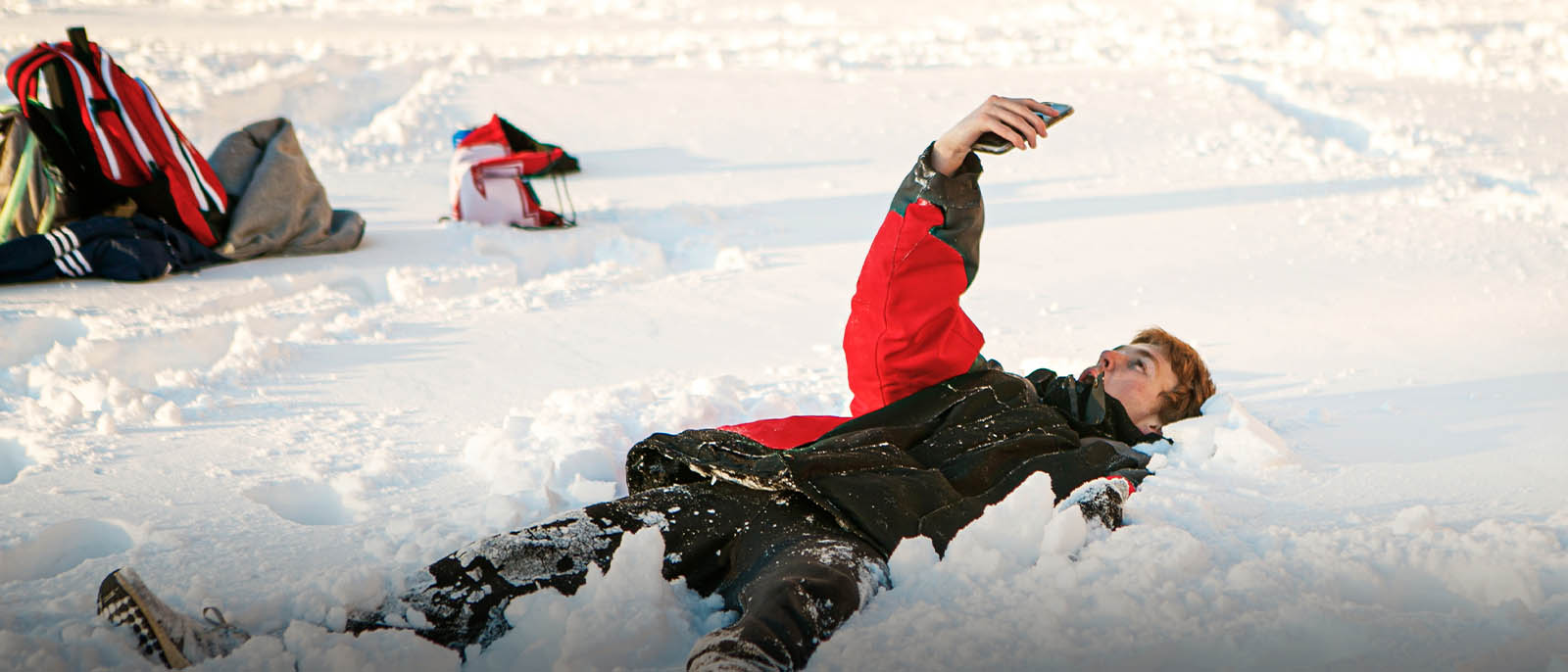 A student laying in the snow taking a selfie