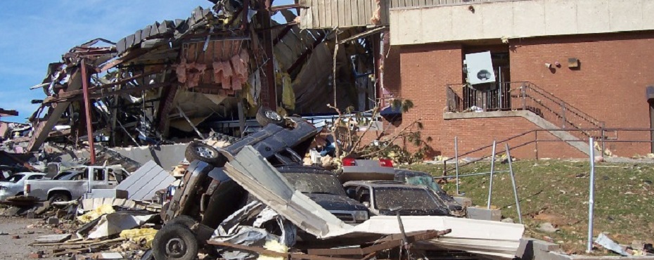 Building and cars partially destroyed by Tornado. Roof crushed in and cars lying on side