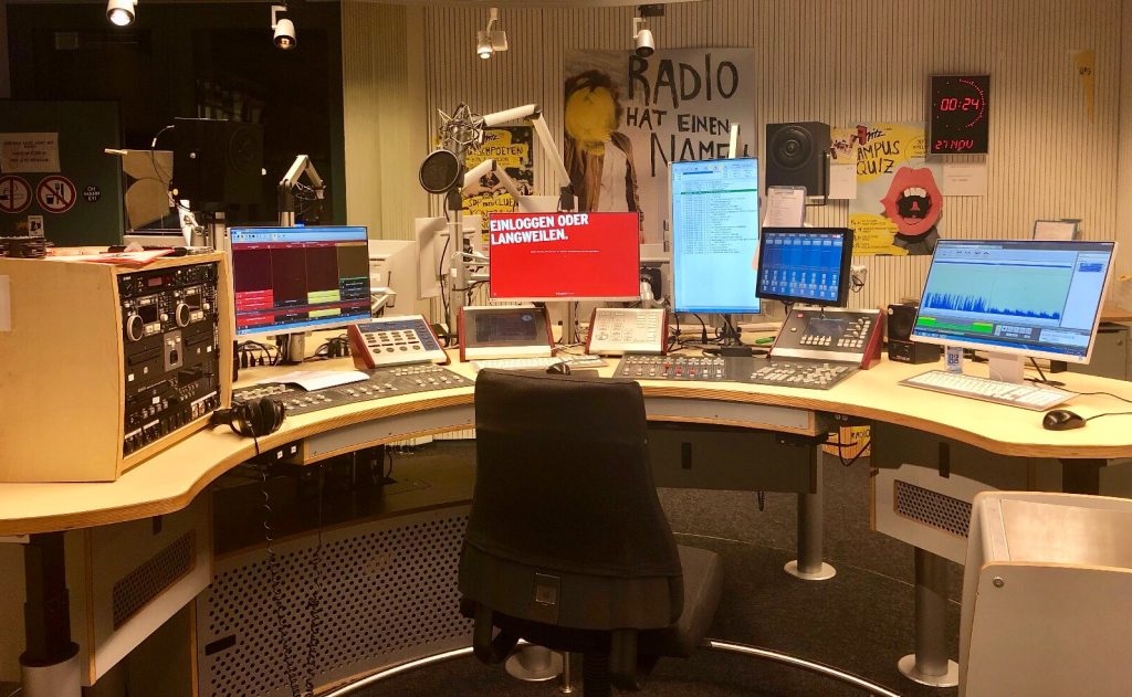 Ein Radiostudio mit Mischpulten, Mikrofonen, Kopfhörern und mehreren Monitoren