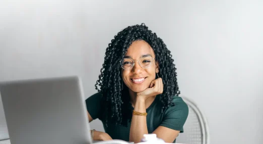 Happy woman sitting at table with laptop