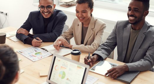 Photo of three people smiling while having a meeting