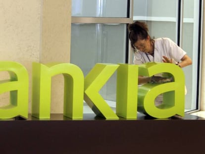 Una trabajadora limpia el logo de Bankia.