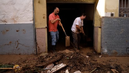 Vecinos de Chiva limpian las calles anegadas de barro.