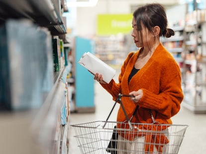 Una joven consulta la información de un cartón de leche en un supermercado.