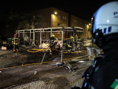 Los bomberos apagan el fuego en un autobús público incendiado en el barrio de Zambujal durante los disturbios desatados tras la muerte de un vecino, tiroteado por la policía.