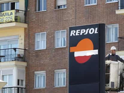 Un operario trabaja en un panel de Repsol en una gasolinera de Madrid.