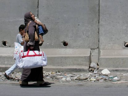 Una palestina y sus hijos caminan por la localidad de Aram.