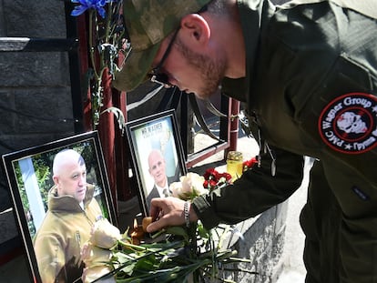 Un miembro del grupo mercenario privado Wagner rinde homenaje a Prigozhin (foto de la izquierda) y Utkin, frente a una oficina de Wagner, este jueves en Novosibirsk.