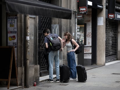 Turistas frente a un portal a punto de entrar en un piso turístico de Barcelona, este verano.