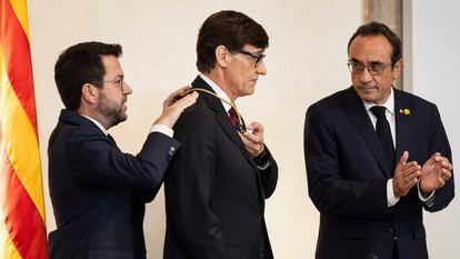 El 'expresident' Pere Aragonès coloca la medalla de la Generalitat a Salvador Illa ante el aplauso del 'president' del Parlament, Josep Rull.