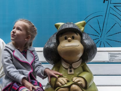 Luisa, la hija del escultor Pablo Irrgang, se sienta junto a la escultura de Mafalda de su padre durante la inauguración de dos esculturas más de los personajes de Quino, el 29 de septiembre de 2014 en Buenos Aires.