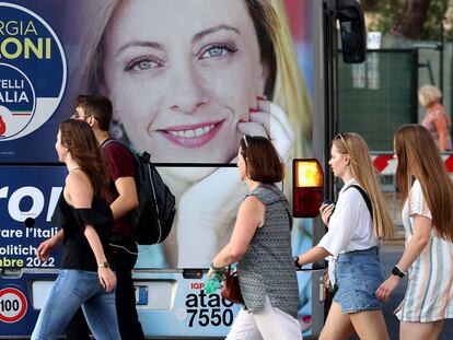 Un grupo de jóvenes, ante una publicidad electoral de Meloni, en Roma.