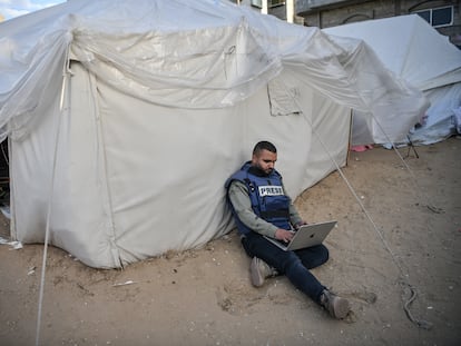 Un periodista sentado junto a una tienda de campaña mientras intenta conectarse a internet el 14 de enero en Rafah, Gaza.