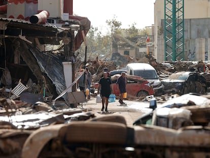 Varias personas caminan entre el lodo acumulado en las calles a causa de las intensas lluvias caídas por la fuerte dana, este jueves en Catarroja.