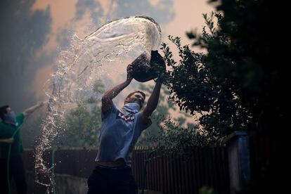 Un hombre lanza un cubo de agua para apagar el incendio forestal en Oliveira De Azemeis, Portugal, este lunes.
