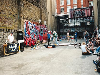 Un DJ pincha en el aparcamiento mientras un grupo de jóvenes baila break dance mientras otros pintan graffitis.