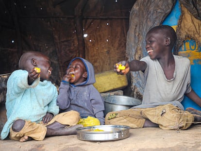 Los hermanos ugandeses Rahim, Emmanuel y lobuka (de izquierda a derecha) disfrutan de una comida en el campo de Bidi bidi, en el noroeste de Uganda, en 2022.