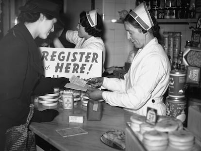 A una mujer le recortan los cupones de la cartilla de racionamiento después de recibir su azúcar y su mantequilla para la semana durante la Segunda Guerra Mundial