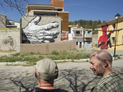 Integrantes del colectivo MIAU contemplan algunas obras pintadas en las fachadas de Fanzara, en una imagen de archivo.