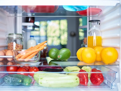 Opened fridge from the inside full of vegetables, fruits and other groceries.