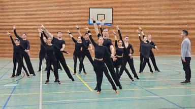 Die Lateinformation des Bremer Grün-Gold--Club während einer Probe in schwarzer Trainingskleidung bei einer Pose der Choreografie Freedom and Peace mit Trainer Roberto Albanese.