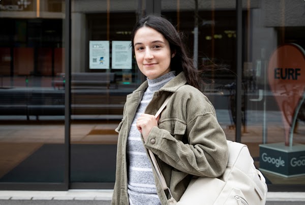 Eine junge Frau mit Rucksack steht vor der Google-Zentrale in der Schweiz.