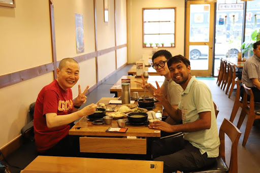 Dnyan, Kyehyun et son père sourient et font le signe de la paix pendant un repas