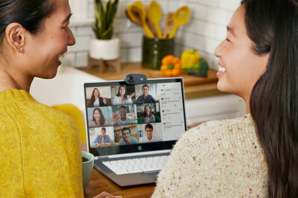 Deux personnes assises dans une cuisine échangent un sourire et participent à un appel Google Meet.