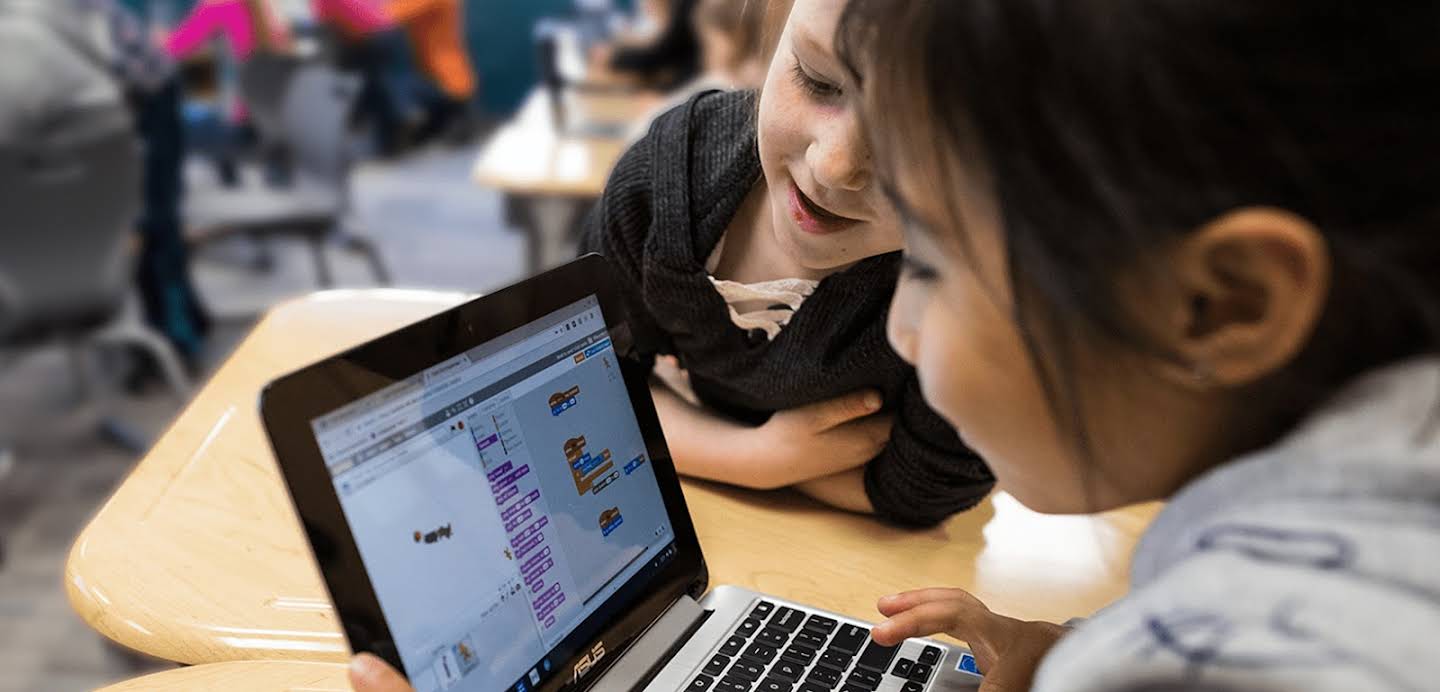 Two students sharing a laptop to learn together at school.