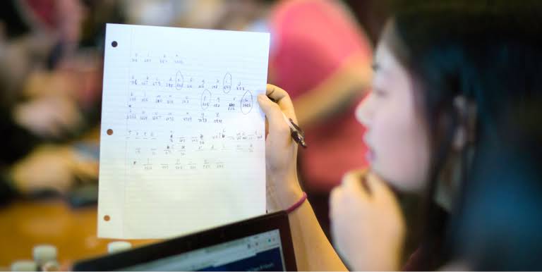 A student looking at a piece of paper with numbers circled on it.